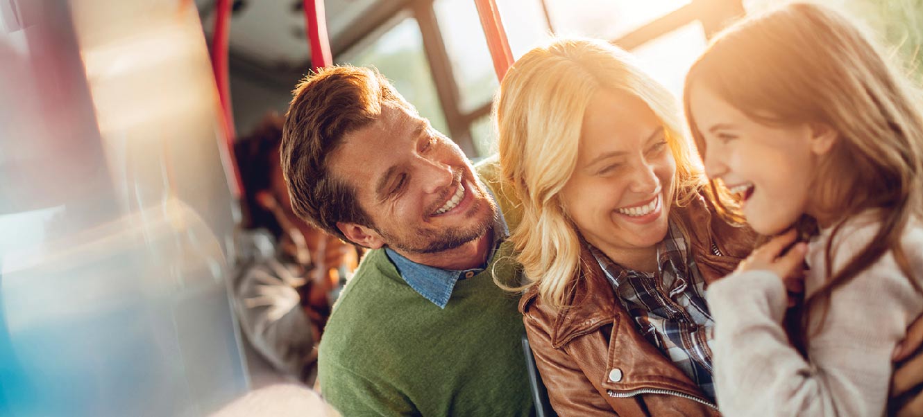 Young family smiling on a commuter train.