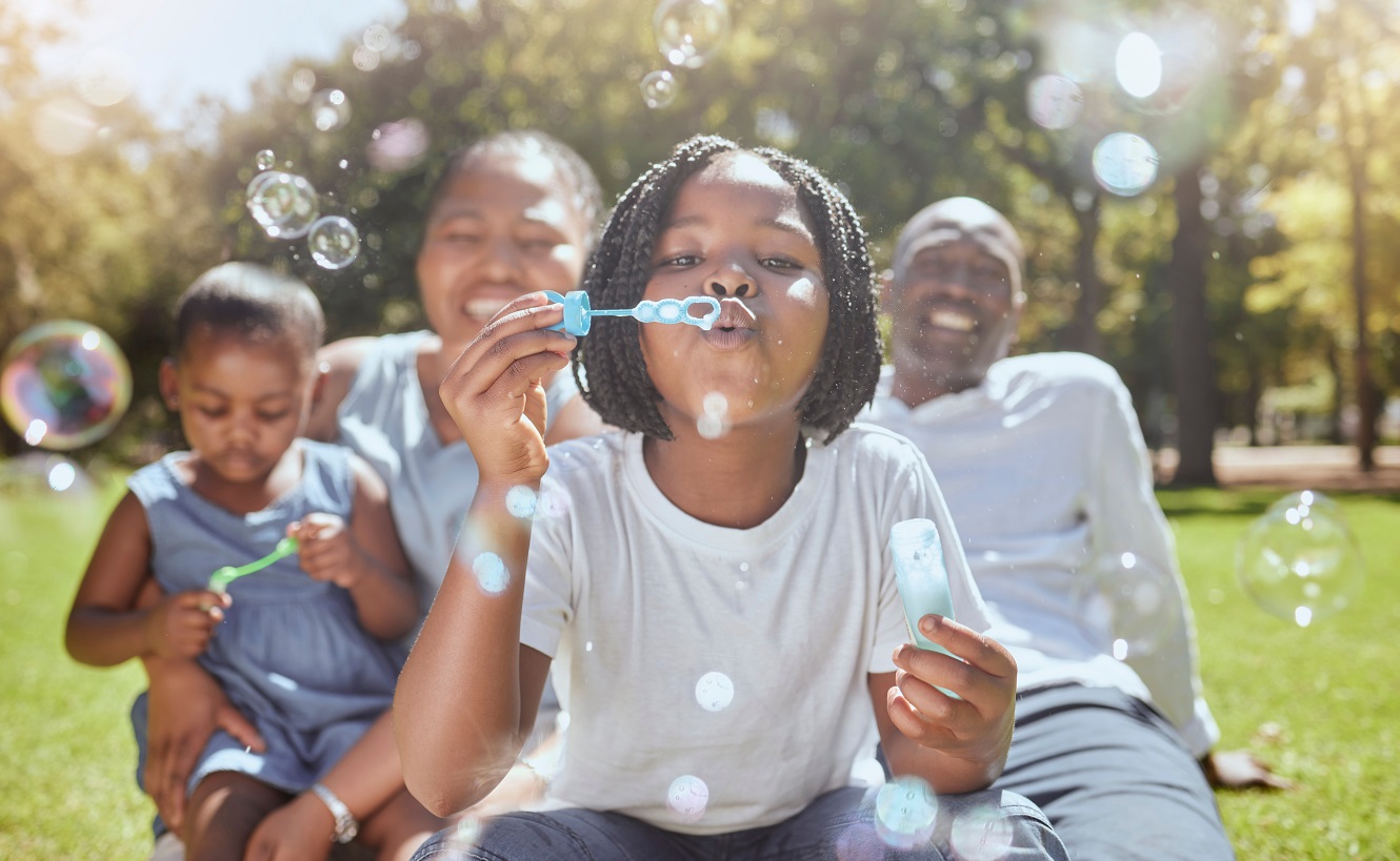 Girl blowing bubbles with family
