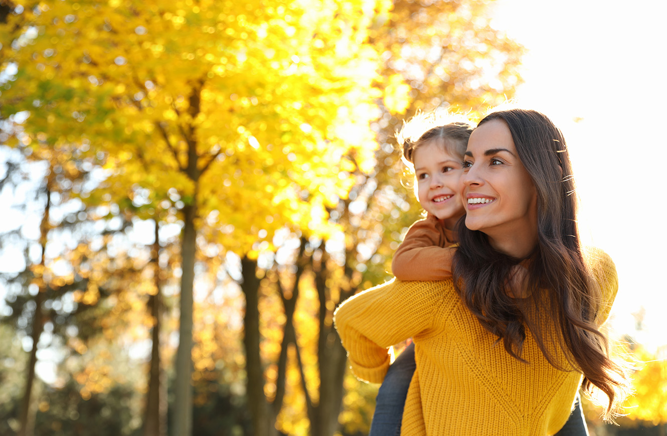 mom holding daughter outside around trees