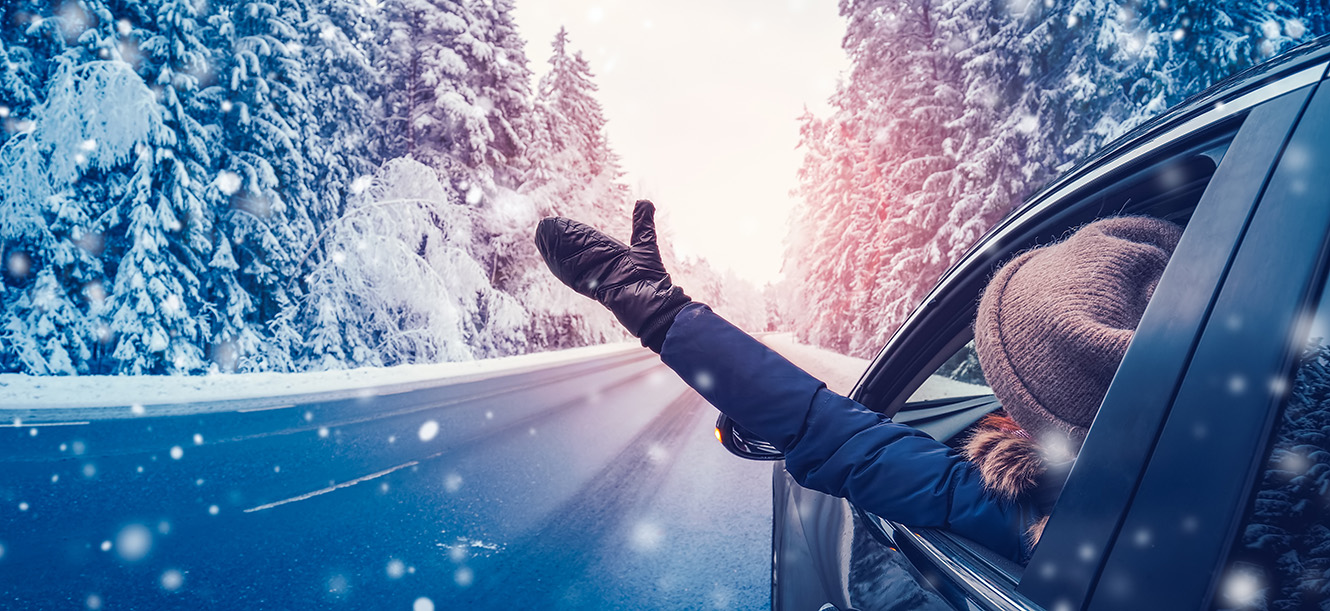 woman driving with hand outside window in winter