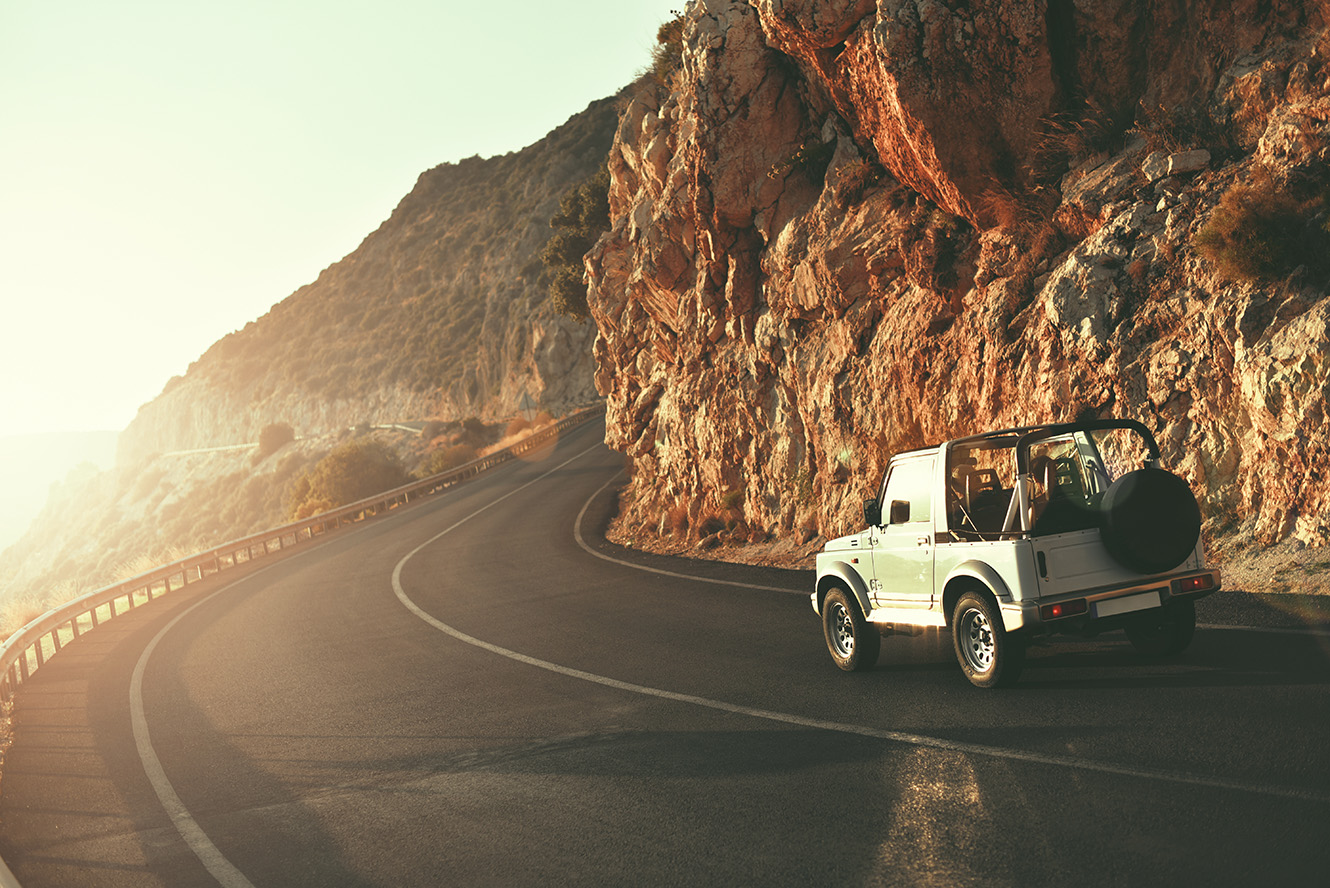 suv driving on road into the sunset